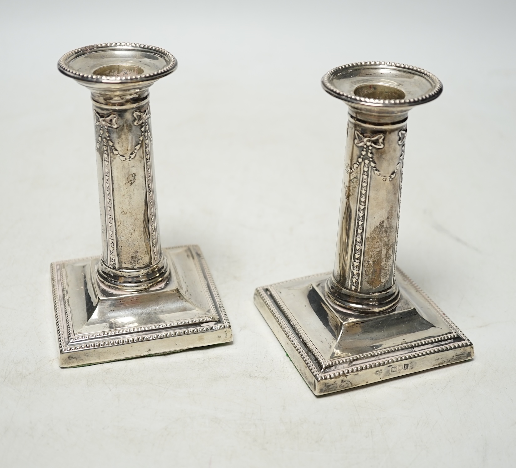 A pair of Edwardian silver dwarf candlesticks, by Goldsmiths & Silversmiths Co Ltd, London, 1904, 12.1cm, weighted. Condition - poor to fair